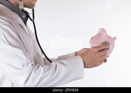 Arzt hören auf das Herz ein rosa Sparschwein mit einem Stethoskop in einem konzeptionellen Bild in eine Nahaufnahme Seitenansicht isoliert auf weiss mit Textfreiraum Stockfoto