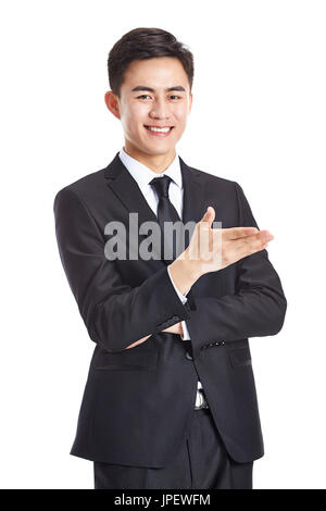 junge asiatische Geschäftsmann in Abendgarderobe gestikulieren eine Einladung, glücklich und lächelnd, isoliert auf weißem Hintergrund. Stockfoto