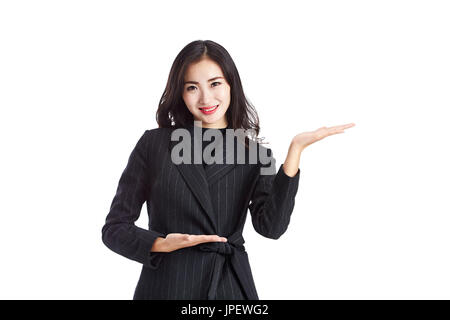 junge und schöne asiatische Geschäftsfrau in Abendgarderobe zu zeigen oder etwas Kunde, isoliert auf weißem Hintergrund zu präsentieren. Stockfoto