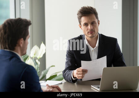 Misstrauisch Geschäftsmann hält Dokument lesen schlecht Lebenslauf an Stockfoto