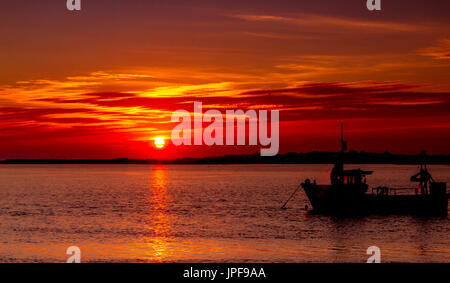 Herrlicher Sonnenuntergang über den Fluss Stour an Mudeford Quay, Dorset, mit Booten in Silhouette an einem schönen Herbstabend Stockfoto