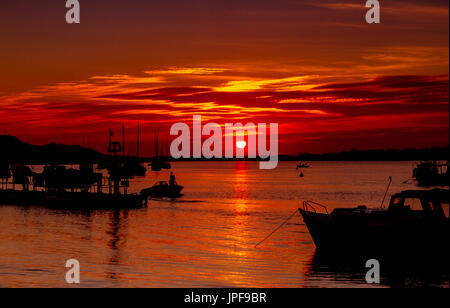 Herrlicher Sonnenuntergang über den Fluss Stour an Mudeford Quay, Dorset, mit Booten und Brücken in Silhouette an einem schönen Herbstabend Stockfoto