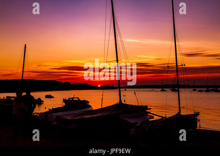 Herrlicher Sonnenuntergang über den Fluss Stour an Mudeford Quay, Dorset, mit Booten in Silhouette an einem schönen Herbstabend Stockfoto