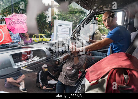 London, UK. 1. August 2017. Ein Mann in einem weißen Lieferwagen versucht, fahren durch den Rising Up Umwelt Demonstranten Blockiing Verkehr auf der belebten Marylebone Road unweit von Baker St für einen zweiten "Staying Alive" Straßensperre Disco Protest zu sensibilisieren und rufen zu dringendem Handeln über die hohe Schadstoffbelastung von Verkehr auf den Straßen Londons, die 10.000 vorzeitige Todesfälle pro Jahr verursachen. Sie standen und saßen auf der Straße vor dem Wagen und sich geweigert zu gehen.  Peter Marshall/Alamy Live-Nachrichten Stockfoto