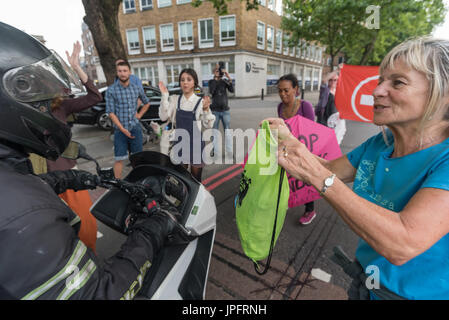 London, UK. 1. August 2017. Ein Mann auf einem Motorrad bahnt sich seinen Weg gefährlich durch Rising Up Umwelt Demonstranten tanzen auf der belebten Marylebone Road unweit von Baker Street im zweiten Teil ihres "Staying Alive" Straßensperre Disco Protestes zu sensibilisieren und rufen zu dringendem Handeln über die hohe Schadstoffbelastung von Verkehr auf den Straßen Londons, die 10.000 vorzeitige Todesfälle pro Jahr verursachen. Demonstranten argumentieren mit ihm als seine Laufwerke Trog ignorieren. Peter Marshall/Alamy Live-Nachrichten Stockfoto