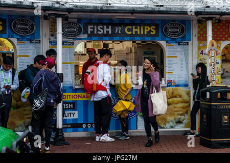 Brighton, UK. 2. August 2017. Großbritannien Wetter. Eine Gruppe von jungen chinesischen Touristen kaufen Fish &amp; Chips im Regen am Strand von Brighton, Brighton, East Sussex, UK. Bildnachweis: Grant Rooney/Alamy Live-Nachrichten Stockfoto