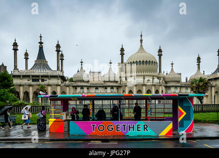 Brighton, UK. 2. August 2017. Großbritannien Wetter. Menschen Schutz vor dem Regen in einer bunten Wartehalle, Brighton, East Sussex, UK. Die Haltestelle wurde vorübergehend für das kommende Wochenende in Brighton Pride gemalt. Bildnachweis: Grant Rooney/Alamy Live-Nachrichten Stockfoto