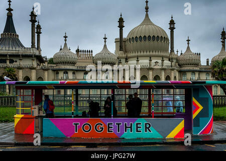 Brighton, UK. 2. August 2017. Großbritannien Wetter. Menschen Schutz vor dem Regen in einer bunten Wartehalle, Brighton, East Sussex, UK. Die Haltestelle wurde vorübergehend für das kommende Wochenende in Brighton Pride gemalt. Bildnachweis: Grant Rooney/Alamy Live-Nachrichten Stockfoto