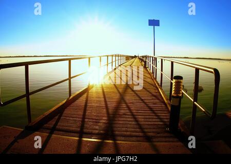 Morgen im Hafen. Touristen gehen auf Pier Bau über dem Meeresspiegel. Sonnigen, klaren, blauen Himmel, Wasser glätten Stockfoto