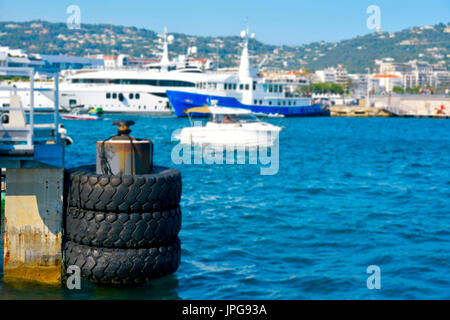 ein Blick auf den Hafen von Cannes an der französischen Riviera, mit einem rostigen Dock im Vordergrund und einige unkenntlich festgemachten Yachten im Hintergrund Stockfoto