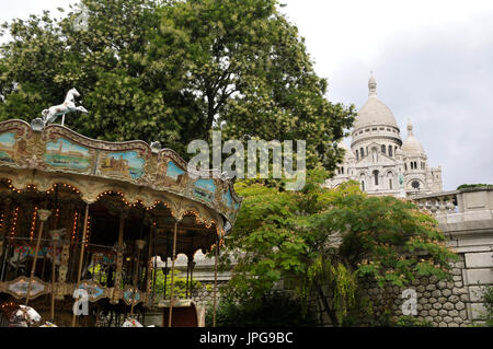 Ein Jahrmarkt mit der Basilika der Heiligen Herzen von Paris im Hintergrund am Montmartre, Paris, Frankreich. Stockfoto