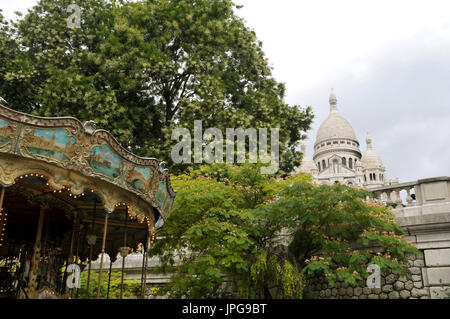 Ein Jahrmarkt mit der Basilika der Heiligen Herzen von Paris im Hintergrund am Montmartre, Paris, Frankreich. Stockfoto