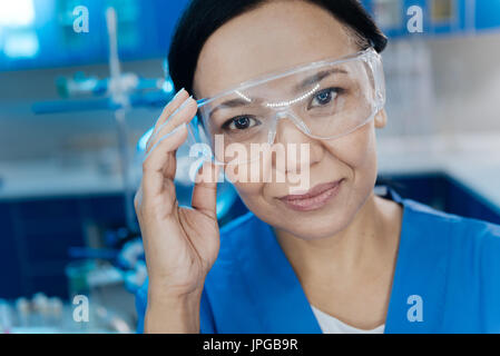 Fröhliche attraktive Frau hält ihre Schutzbrille Stockfoto