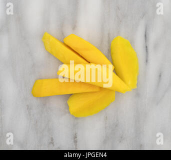 Draufsicht auf mehrere Scheiben frisch geschnittene Mango auf einem grauen Marmor Schneidebrett. Stockfoto