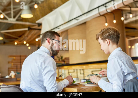 Junge Kollegen sitzen im Café, zu Mittag und Pläne zu besprechen Stockfoto