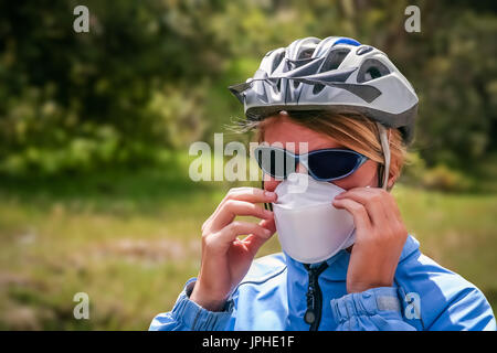Weibliche Radfahrer tragen eine schützende Gesichtsmaske, die verhindern, dass Einatmen von vulkanischem Staub Asche nach Ausbruch im südlichen Patagonien, Chile Stockfoto