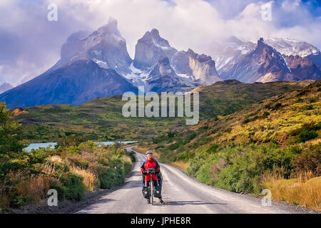 Mädchen mit ihrem Fahrrad auf dem Weg zu den beeindruckenden Gipfeln der Cuernos del Paine im Nationalpark Torres del Paine, Chile, Südamerika Stockfoto