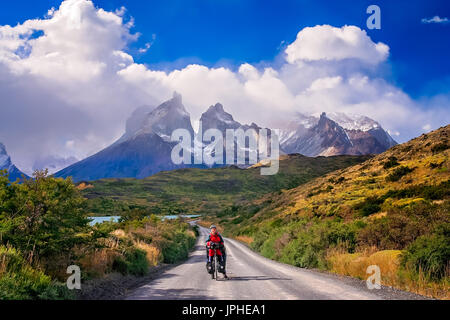 Mädchen mit ihrem Fahrrad auf dem Weg zu den beeindruckenden Gipfeln der Cuernos del Paine im Nationalpark Torres del Paine, Chile, Südamerika Stockfoto