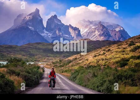 Mann auf einem Fahrrad auf der Straße, die zu den beeindruckenden Cuernos Del Paine Peaks im Torres del Paine Nationalpark, Chile, Südamerika Stockfoto