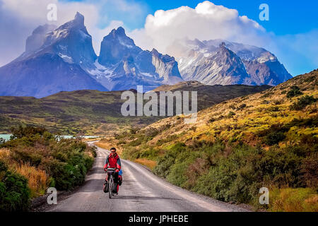 Mann auf einem Fahrrad auf der Straße, die zu den beeindruckenden Cuernos Del Paine Peaks im Torres del Paine Nationalpark, Chile, Südamerika Stockfoto