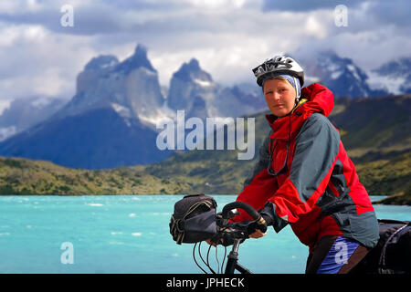 Mädchen mit ihrem Fahrrad auf dem Weg zu den beeindruckenden Gipfeln der Cuernos del Paine im Nationalpark Torres del Paine, Chile, Südamerika Stockfoto