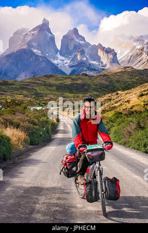 Mann auf einem Fahrrad auf der Straße, die zu den beeindruckenden Cuernos Del Paine Peaks im Torres del Paine Nationalpark, Chile, Südamerika Stockfoto