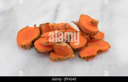Mehrere Scheiben frischen Kurkuma auf ein grauer Marmor Schneidebrett. Stockfoto