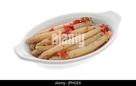 Marinierter weißer Spargel Stiele mit Gewürzen in Keramik Auflaufform isoliert auf einem weißen Hintergrund. Stockfoto