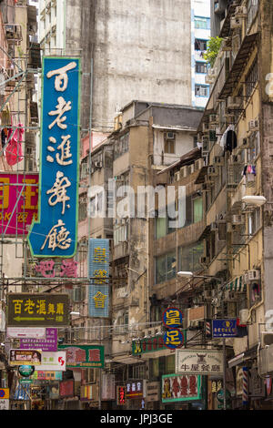 Kakophonie von chinesischen und englischen Schilder an heruntergekommenen Gebäuden im kaufmännischen Bereich von Kowloon, Hong Kong Stockfoto