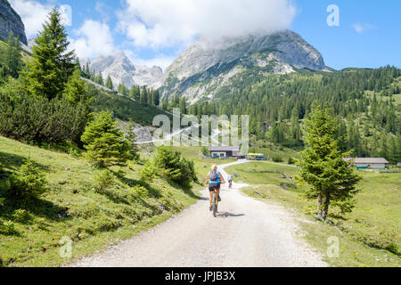 Radfahrer, die Annäherung an die Seebenalm Restaurant mit der Sonnenspitze Berg hinter der Mieminger Gebirge Palette, Ehrwald, Tirol, Österreich Stockfoto