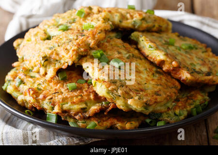 Hot Zucchini-Pfannkuchen mit Frühlingszwiebeln auf einer Platte Nahaufnahme auf einem Tisch. Horizontale Stockfoto