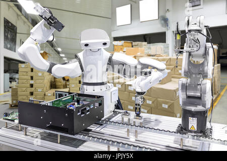 Industrieroboter, die Installation von eines Computerchips im Fließband Hersteller Fabrik, Steuerung des Roboterarms für die Durchführung, Abgabe, Material-ha Stockfoto