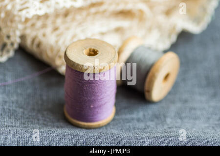 Vintage Holz Spulen mit lila und grau Threads auf gefalteten Wollstoff, Wollweiß Baumwollspitze, Hobby swing-Konzept, Exemplar, Header für website Stockfoto