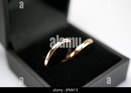 Elegante goldene Eheringe leuchten in einer eleganten schwarzen Box und symbolisieren ewige Liebe in einer zeitlosen und raffinierten Präsentation. Stockfoto