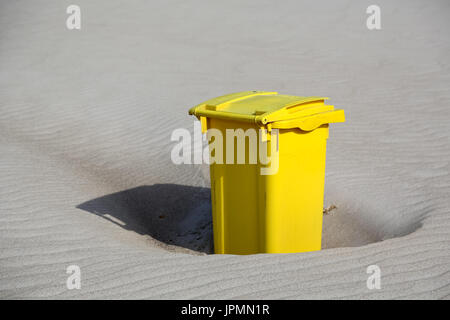 Eine gelbe Mülltonne befindet sich auf dem Sand der Ostsee-Strand in Kolberg in Polen Stockfoto