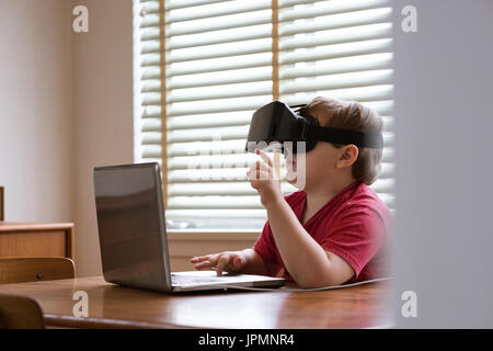 Junge mit Vr-Brille während mit Laptop zu Hause Stockfoto