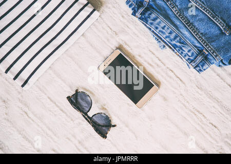 Flach aus einer modischen woman fashion Outfit. nach oben Blick auf ein paar der Leopard Sonnenbrille und ein elegantes Smartphone. Perfekte Feder outfit Accessoires. Stockfoto