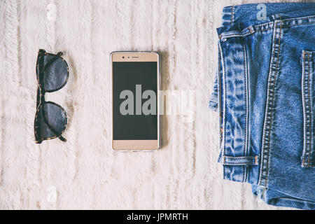 Flach aus einer modischen woman fashion Outfit. nach oben Blick auf ein paar der Leopard Sonnenbrille und ein elegantes Smartphone. Perfekte Feder outfit Accessoires. Stockfoto