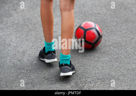 Ein Jugendlicher üben fußballerischen Fähigkeiten auf eine asphaltierte Spielbereich Stockfoto