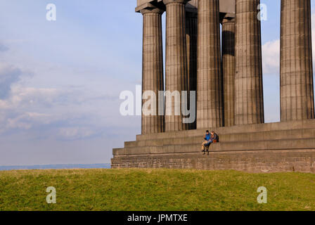 Ein paar sitzt am National Monument in Edinburgh. Das National Monument of Scotland ist ein halbfertigen Denkmal auf der Oberseite Carlton Hill. Stockfoto