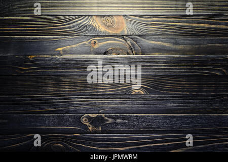 Schwarzes Holz gestreifte Textur mit Vignette. Eine Holzoberfläche durch ein Ort des Lichts beleuchtet Stockfoto