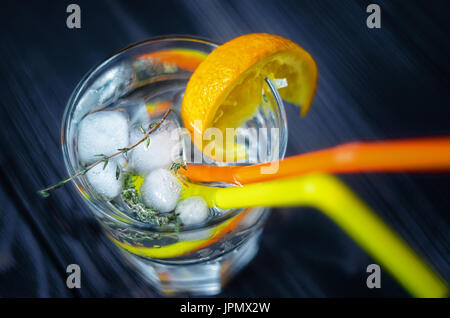 Getränke mit Eis, verziert mit einer orange Slice und Rosmarin Draufsicht. Zwei Strohhalme in Glas. Stockfoto