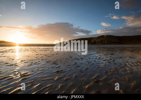 Sonnenuntergang am Strand bei Ebbe in Cemaes Bay, Anglesey Wales UK Stockfoto