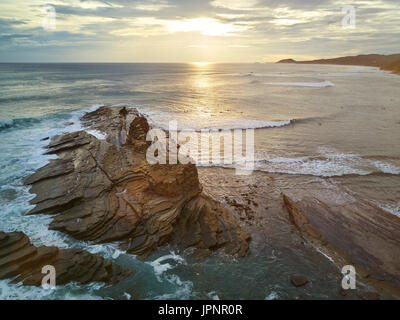 Surfer haben es Surfen im Sonnenuntergang in Nicaragua. Surfer neben großen Felsen Stockfoto