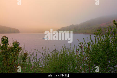 Landschaft am nebligen Morgen im Ladybower Reservoir mit rosa Sonnenaufgang über das ruhige Wasser des Sees und Ashopton Viadukt im Abstand in England Stockfoto