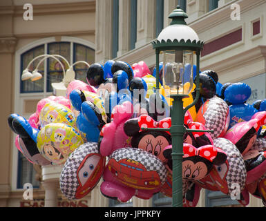 Eine Reihe von bunten Luftballons mit Minnie Mouse, Mickey Mouse und Autos mit einem alten altmodischen Lamp Post im Vordergrund. Stockfoto