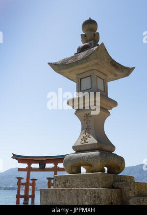 Nahaufnahme von einem gravierten konkrete Schrein mit Torii Tor von Miyajima im Hintergrund. Stockfoto