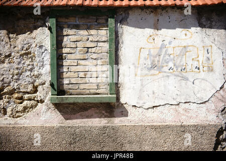 Eine rustikale Wand versetzt und gebrochene Steine mit Dachziegel und einem ummauerten Fensterrahmen. Stockfoto