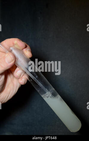 Eine Person außerhalb des Rahmens bläst Luft Trog eine Lösung von Calciumhydroxid (Kalkmilch) die CO2-Emissionen von dem Ausatmen verursacht eine Reaktion, wo solide Kreide Stockfoto