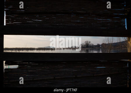 Einen schönen Seeblick gesehen durch eine schmale Öffnung in einem Reed-panel Stockfoto